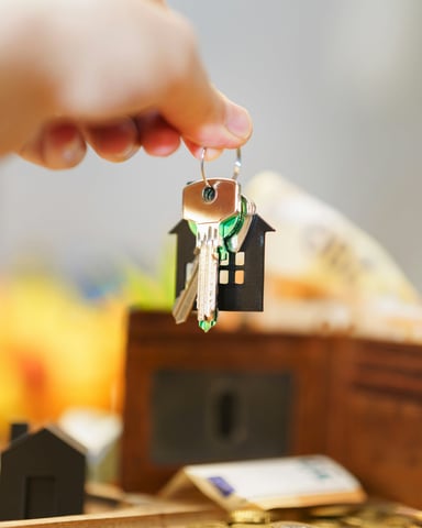 Hand holding house keys with a house-shaped keychain