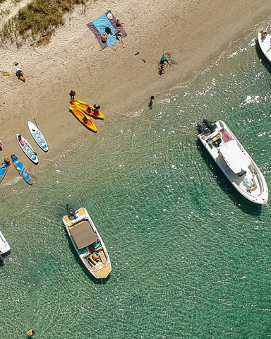 Aerial view of beach with paddleboards and boats in clear turquoise water