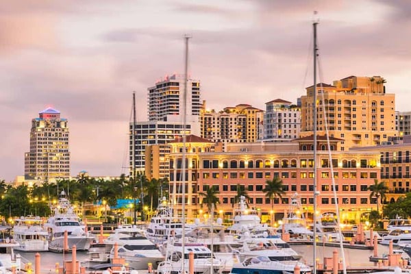Marina with moored boats and waterfront high-rise buildings at sunset